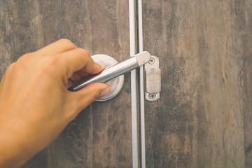 Close-up finger of left hand to locking or unlocking the door of toilet, Lock the bathroom door from the inside of the bathroom, Hand with door handle.