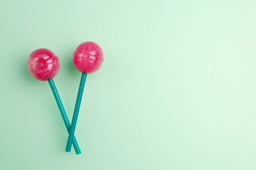 Two red lollipop on mint green pastel background. Sweet lollipop concept. Copy space for text.