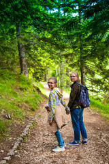Naklejka na ściany i meble Teenagers with backpacks hiking in forest. Summer vacation.