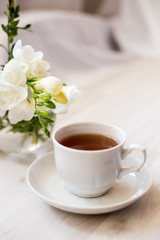 Obraz na płótnie Canvas cup of tea and white freesia flower