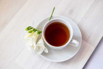 cup of tea and white freesia flower