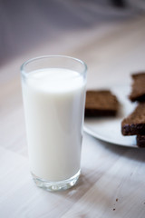 a glass of milk and slices of rye bread on a saucer