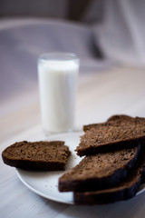 a glass of milk and slices of rye bread on a saucer