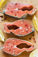 Steak raw red fish with lemon and spices dark background.