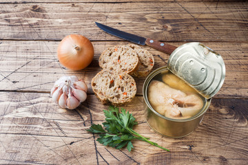 Ingredients for soup jar with pink salmon fish, pieces of bread, onion and garlic with greens on wooden background.