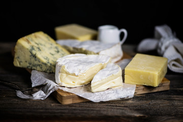camembert cheese and a set of cheeses on a wooden board on a dark background