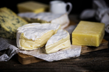 camembert cheese and a set of cheeses on a wooden board on a dark background