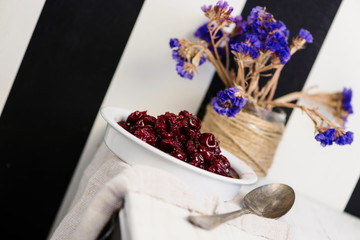 homemade berry cherry jam in a white plate on a wooden table