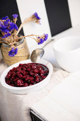 homemade berry cherry jam in a white plate on a wooden table