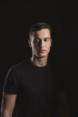 Obraz premium Beautiful, slender young man in black t-shirt on black background and on the street