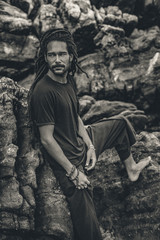Fototapeta na wymiar Handsome young man with dreadlocks outdoors. male model at the rocks