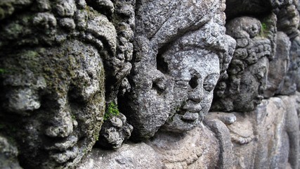 Ancient stone carving of women's faces in Borobudur, or Barabudur, world's largest Buddhist temple and a UNESCO World Heritage Site, located in Magelang, Central Java, Indonesia.