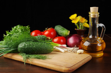 Vegetables for salad and a bottle of sunflower oil on a dark background