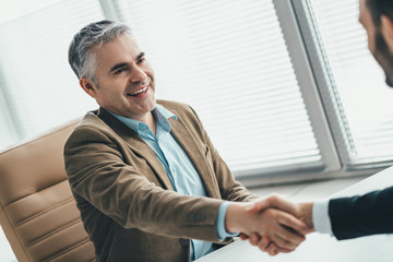 The happy businessmen handshaking in the office