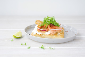 Smoked salmon sandwich with cream cheese. White wooden background
