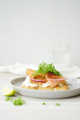 Smoked salmon sandwich with cream cheese. White wooden background