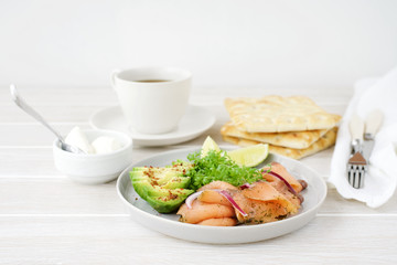 Avocado and smoked salmon on plate. Healthy breakfast. White wooden background