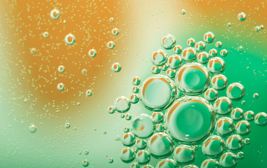 Abstract blurred green with yellow liquid texture background with circles of different size and bubbles. Cropped shot, macro, horizontal, nobody, gradient.