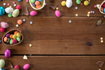 Obraz premium easter, sweets and confectionery concept - chocolate eggs and candy drops on wooden background