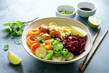 Buddha bowl with chicken meatballs, noodles, carrots, cucumbers, red cabbage and green onions