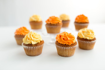 food, pastry and confectionery concept - cupcakes with buttercream frosting over white background