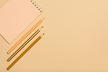 School supplies. Notebook and color pencils on beige background.