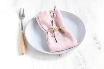 Easter table setting idea, minimal decoration - pink napkin, fork, willow banch, white wooden table