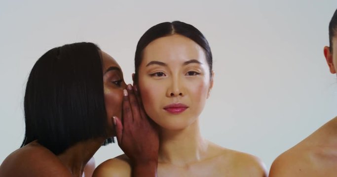 Slow motion of beautiful young smiling women of different ethnicities with perfect firm and slim body in white bathing towels whispering their beauty secrets in the ear and having fun. 