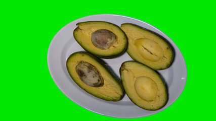 Avocado in a dish on a green background