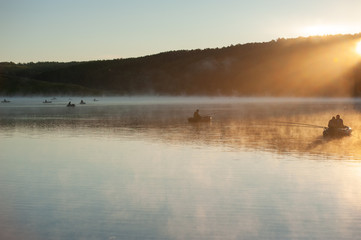 Obraz na płótnie Canvas the lake with the fishermen of the sun's rays mist