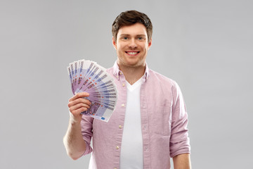 money, finance, business and people concept - smiling young man with fan of five hundred euro bank...
