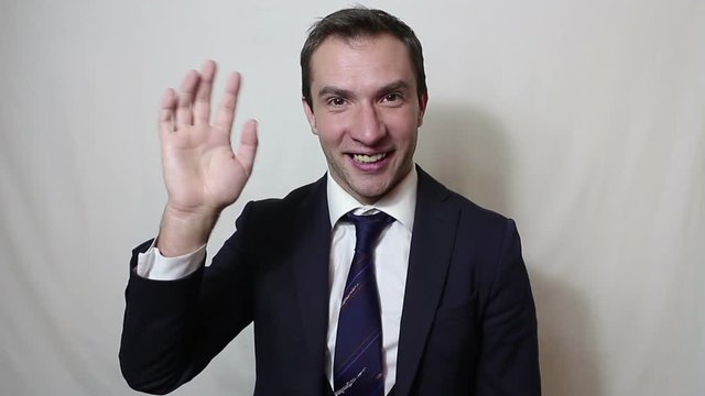 Young beautiful businessman in blue suit smiling and waving her hand greeting customers.Portrait on a white background.
