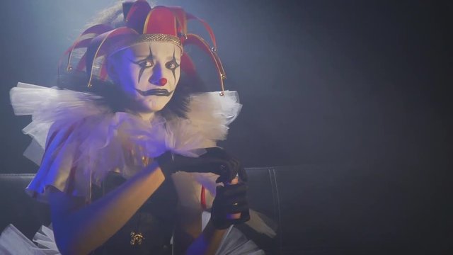 Frowning clown woman with white and black old makeup and a red hat, slow motion