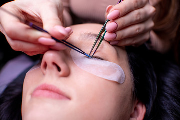 Beauty salon, eyelash extension procedure close up. Beautiful woman with long hair. Personal care