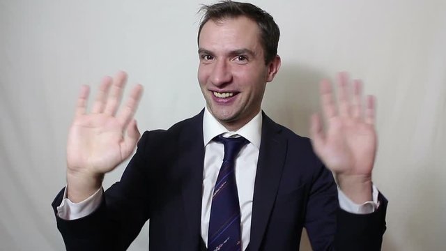Young beautiful businessman in blue suit smiling and waving her hand greeting customers.Portrait on a white background.