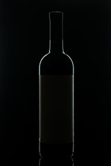 Silhouettes of bottles of red dry wine on a black background.
