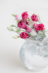 Bouquet of red Eustoma flowers in vase on white background