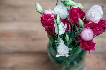 Bouquet of red flowers Eustoma in vase on wooden boards