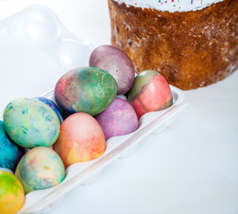 Easter cake and colorful eggs in tray on white background