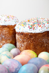 Two Easter cakes and colorful eggs on white background