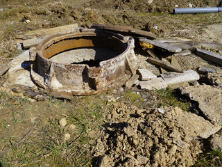 Sewerage hatchway, manhole. Rusty pit cover ring on construction site. Old cast rust iron sewerage...