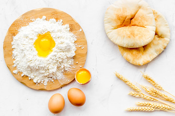 Make bread concept. Flat bread near wheat ears, flour and eggs on white background top view