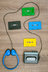 Vintage walkman, colorful cassetes and headphones on the wooden background