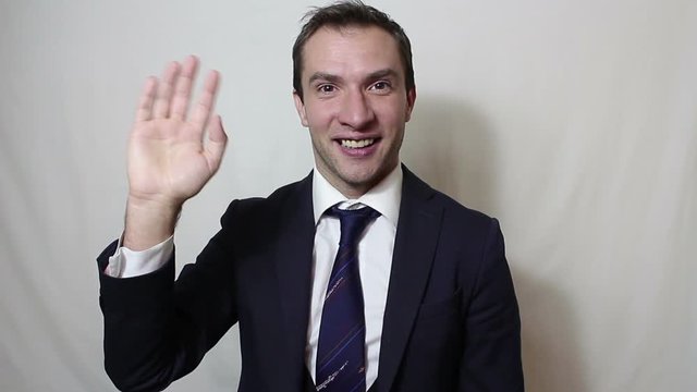 Young beautiful businessman in blue suit smiling and waving her hand greeting customers.Portrait on a white background.