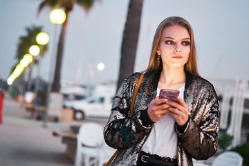 Young beautiful blonde woman walking and writing sms messages