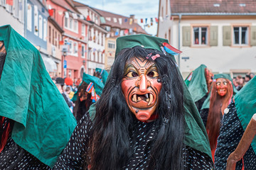 Witch with green hood and big teeth. Street Carnival in Southern Germany - Black Forest.