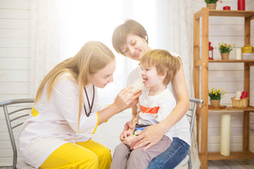 The doctor looks at the throat of little boy