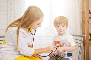 Doctor and patient at home. Little girl is being examined by pediatrician with stethoscope. Medicine and health care
