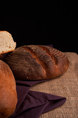 Bakery - gold rustic crusty loaves of bread and buns on black chalkboard background. Still life captured from above