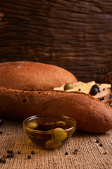 fresh bread baguette with olive oil, olives. cheese and rosemary on wooden background. Teasty breakfast